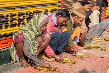 VARANASI, INDIA - JANUARY 25, 2017 : Unidentified poor indian people eating free food at the street near river ganges in Varanasi, Indiaのeditorial素材