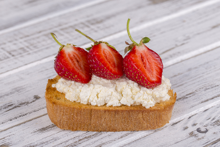 Sandwich of strawberry and cottage cheese on the wooden table, close upの写真素材