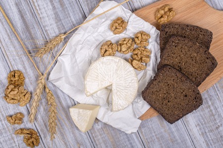 Brie type of cheese. Camembert cheese. Fresh Brie cheese and a slice on a wooden board with walnuts...