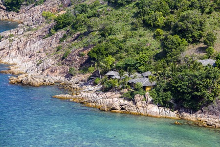 Tropical bungalow on a rocky beach next to the blue sea water. Koh Phangan Island, Thailandの写真素材