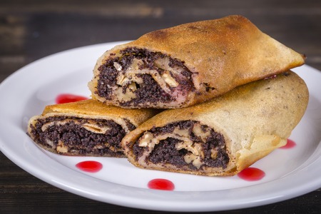 Crepes stuffed with poppy seeds, nuts and honey on white plate for breakfast. Delicious pancakes wrapped with poppy seedsの写真素材