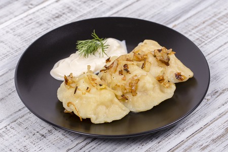 Ukrainian and Russian dish vareniki with mashed potatoes and fried onions and sour cream. Close upの写真素材