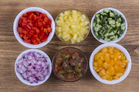 Assortment of colorful vegetables sliced, close up. Fresh peppers, tomatoes, cucumber and onion in bowls. Top view. Healthy foodの写真素材