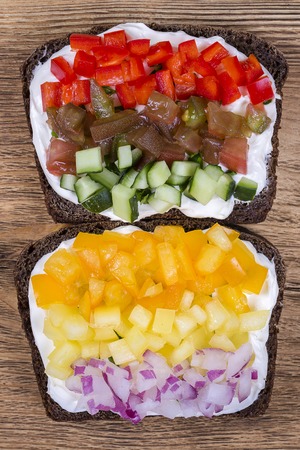 Colorful vegetables sandwich, close up. Fresh peppers, tomatoes, cucumber, onion and cheese on black bread. Top view. Healthy foodの写真素材