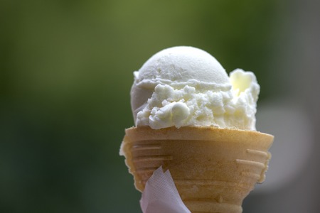 Hand holding an white ice cream in waffle cone, close upの写真素材