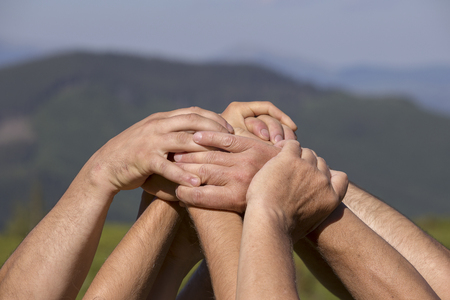 Successful team: many hands holding together on nature background, close up
