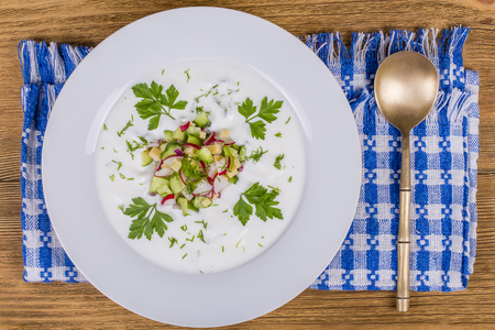Okroshka. Summer light cold vegetable soup with cucumber, radish, eggs and dill on a wooden table. A traditional dish of russian or ukrainian cuisine. Close up, top viewの写真素材