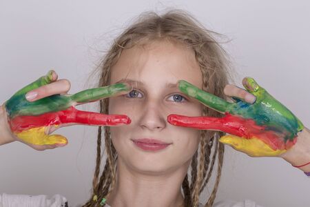 Portrait young girl and hands painted in colorful paints, close upの写真素材