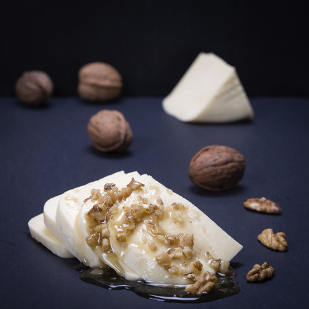 Suluguni cheese, walnut and honey on black slate platter , close upの写真素材