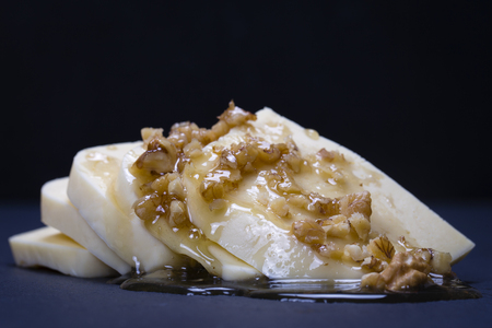 Suluguni cheese, walnut and honey on black slate platter , close upの写真素材