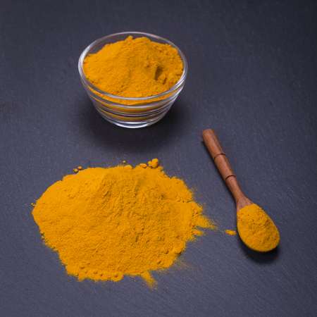 Organic turmeric, curcuma powder on black slate platter background. Curry powder. Close upの写真素材
