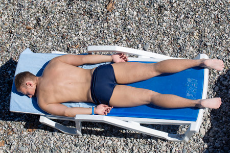 KEMER, TURKEY - OCTOBER 17, 2017 : Man sunbathing on a pebble beach. Kemer it is one of the most popular beach in Turkeyのeditorial素材