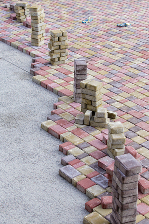 Paving slabs by mosaic close up. Road paving, construction . Fixed tessellated sidewalk tile. Colored concrete paving slabの写真素材