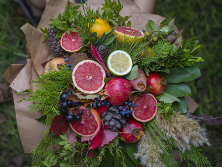 Bouquet of plants and fresh citrus, wrapped in coarse paper, close up, top viewの写真素材