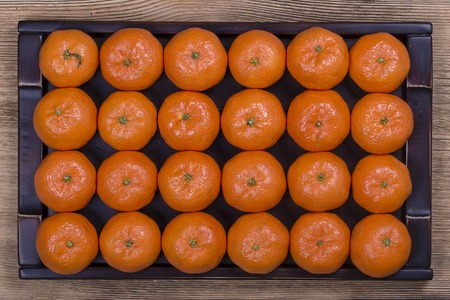 Fresh orange, tangerine fruit, mandarin pattern background on a wooden tray, close up, top viewの写真素材