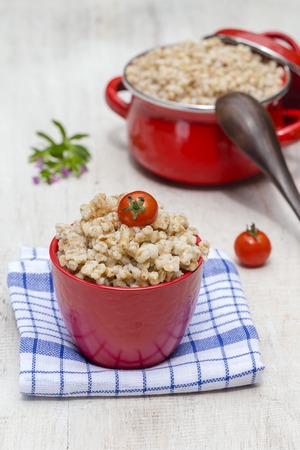 Red bowl and pan with boiled wheat porridge - traditional meal in Ukraine, Belarus and Russia. Close upの写真素材