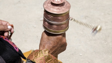 Old hands of a Tibetan woman holding prayer buddhist wheel at a Hemis monastery, Leh district, Ladakh, Jammu and Kashmir, north India. Close upの写真素材