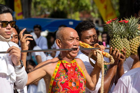 PHUKET, THAILAND - OCT 17, 2015 : Unknown man using sharp objects to pierce through body to show spiritual strength during a street procession in Vegetarian Festival at Phuket Town, Thailandのeditorial素材