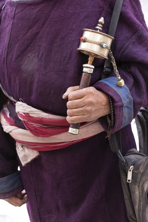 Old hands of a Tibetan man holding prayer buddhist wheel at a Hemis monastery, Leh district, Ladakh,...