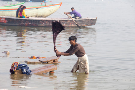 VARANASI, INDIA - JANUARY 26, 2017 : Unidentified Indian men washes clothes in the holy water of the river Ganges at cold foggy winter morning. Varanasi. Uttar Pradesh, Indiaのeditorial素材