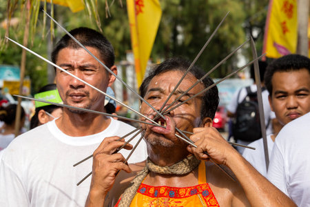 PHUKET, THAILAND - OCT 17, 2015 : Unknown man using sharp objects to pierce through body to show spiritual strength during a street procession in Vegetarian Festival at Phuket Town, Thailandのeditorial素材