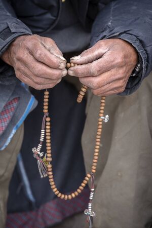 Old hands of a Tibetan man holding prayer buddhist beads at a Hemis monastery, Leh district, Ladakh, Jammu and Kashmir, north India. Close upの写真素材