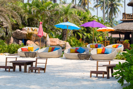 Beautiful beach with swimming pool, coconuts palm trees, rattan daybeds and umbrella in a tropical garden near sea, Thailandのeditorial素材