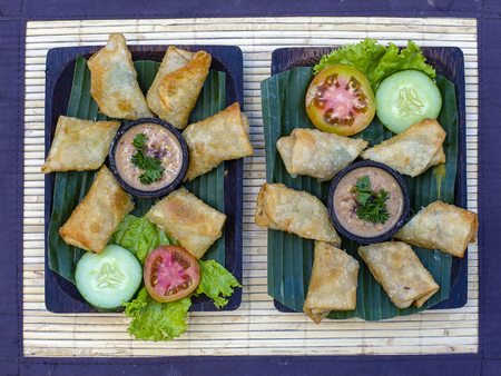 Fried spring rolls on a plate with vegetables and sauce. Close up. Asian food, Ubud, Bali,...