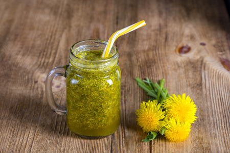 Dandelion yellow flower tea drink in glass mug on wooden table, close up. Concept of healthy eating, herbal flower tinctureの写真素材