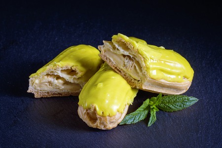 Pistachio eclair in glaze on black background, close up. Traditional French dessertの写真素材