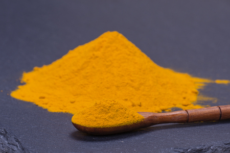 Organic turmeric, curcuma powder on black slate platter background. Healthy curry powder. Close upの写真素材