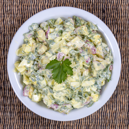 Salad of radish, boiled egg, parsley and sour cream in white bowl - healthy breakfast concept, close upの写真素材