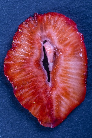 Red strawberry slice on the black background, close up, top viewの写真素材