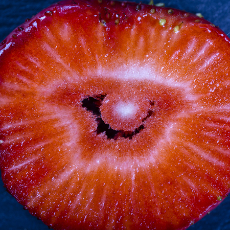Red strawberry slice on the black background, close up, top viewの写真素材