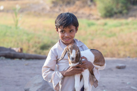 MANDU, INDIA - FEBRUARY 03, 2017 : Unidentified Indian boy on the street with goatling. Poverty is a major issue in Indiaのeditorial素材