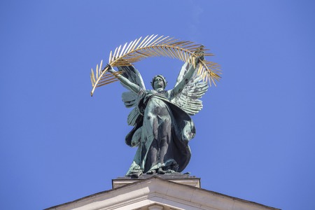 Bronze sculpture genius with gold palm branch and wings on the roof of the opera and ballet theatre in Lviv, Ukraine. Blue sky backgroundの写真素材