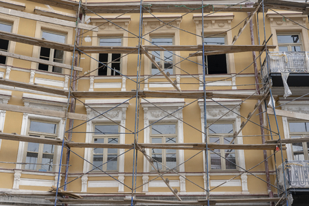 Scaffold on house, renovation. Scaffolding on building, beige wall and window. Scaffolding system in construction.の写真素材