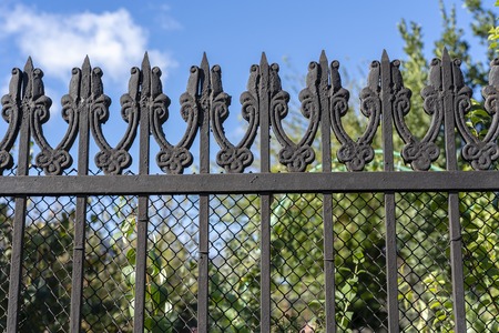 Black metal fence, close up. Beautiful decorative cast iron wrought fence with artistic forging....
