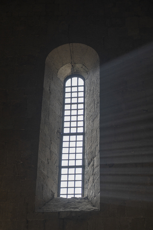 Sunlight penetrates through the arched window in the old orthodox cathedral in historical town...