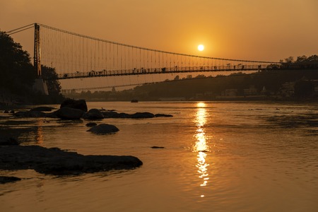 Beautiful view of Ganges river water embankment and bridge at sunset. Rishikesh, India