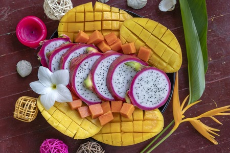 Tropical fruits assortment on a plate, close up. Many colorful ripe tropical fruits background. Mango, papaya and pitahayaの写真素材