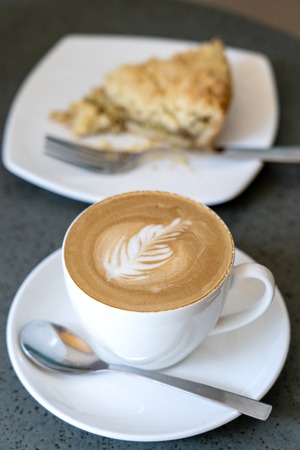 White cup of latte coffee with cake, close upの写真素材