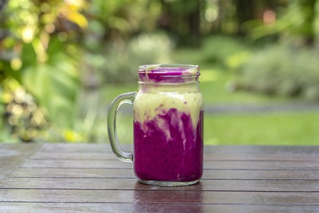 Fresh tropical smoothie with red dragon fruit, green avocado, yogurt and honey in glass mug for breakfast , close up. The concept of healthy eating, superfood . Island Bali, Indonesiaの写真素材