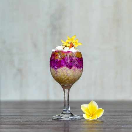 Fruit breakfast in a glass of oatmeal, red dragon fruit, passion fruit, mango and honey in white wooden background, close up. The concept of healthy eating.の写真素材