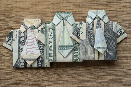Origami shirt made of dollar banknote on wooden background. Close up. Dollar bill T-shirtの写真素材