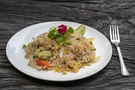 Fried rice with shrimps and vegetables in a white dish on an old wooden table, close up . Thai food , Thai cuisine. Fried rice with seafood in the restaurantの写真素材
