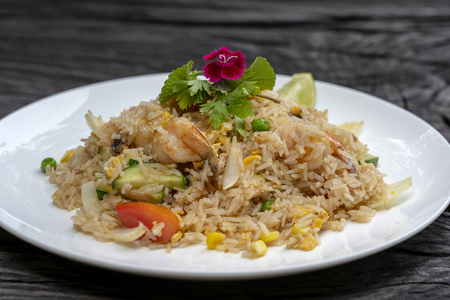 Fried rice with shrimps and vegetables in a white dish on an old wooden table, close up . Thai food , Thai cuisine. Fried rice with seafood in the restaurantの写真素材