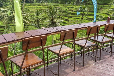 Wooden table and chairs in empty tropical cafe next to rice terraces in island Bali, Indonesia, close upの写真素材
