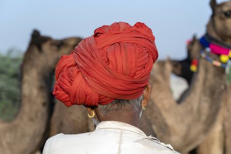 Indian men and herd camels in desert Thar during Pushkar Camel Mela near holy city Pushkar, Rajasthan, India. This fair is largest camel trading fair in the worldの写真素材