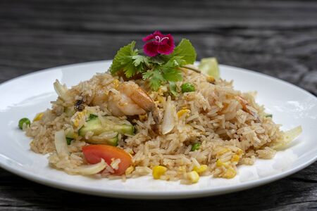 Fried rice with shrimps and vegetables in a white dish on an old wooden table, close up. Thai food, Thai cuisine. Fried rice with seafood in the restaurantの写真素材